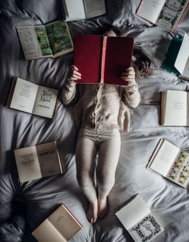 toddler laying in bed reading books