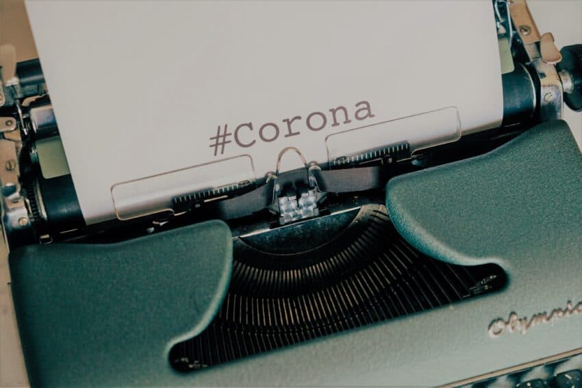 vintage teal-colored typewriter with #Corona typed on white paper