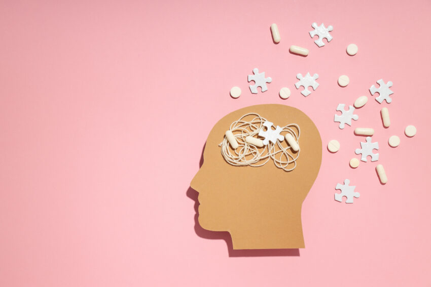 pink background with tan head silhouette featuring cords, puzzle pieces and medicine spilling out depicting mixed signals